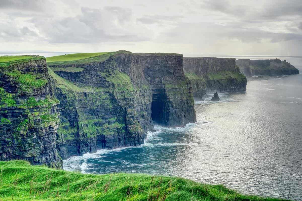 Le Scogliere di Moher in Irlanda con il cielo nuvoloso tipico del clima oceanico irlandese, una delle mete più visitate in estate e primavera