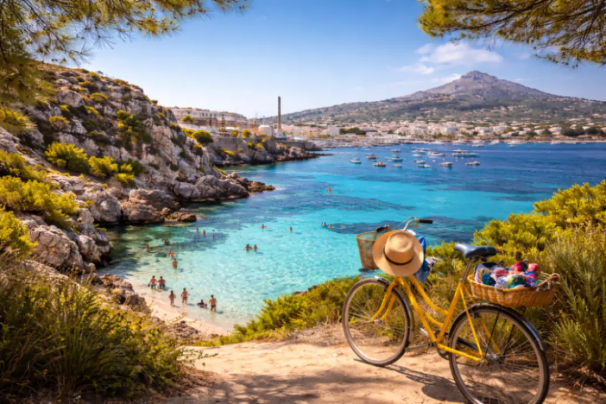 Vista panoramica di una cala di Favignana con mare turchese, scogli, bici gialla e paesaggio costiero dell’isola